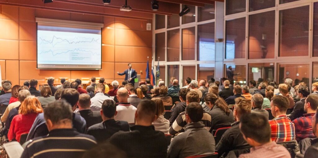 Room of people facing towards a person presenting to the audience